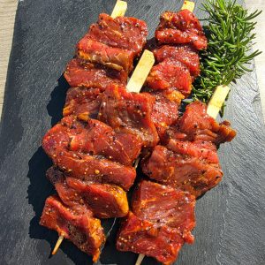 4 black garlic and beef kebabs on a slate platter